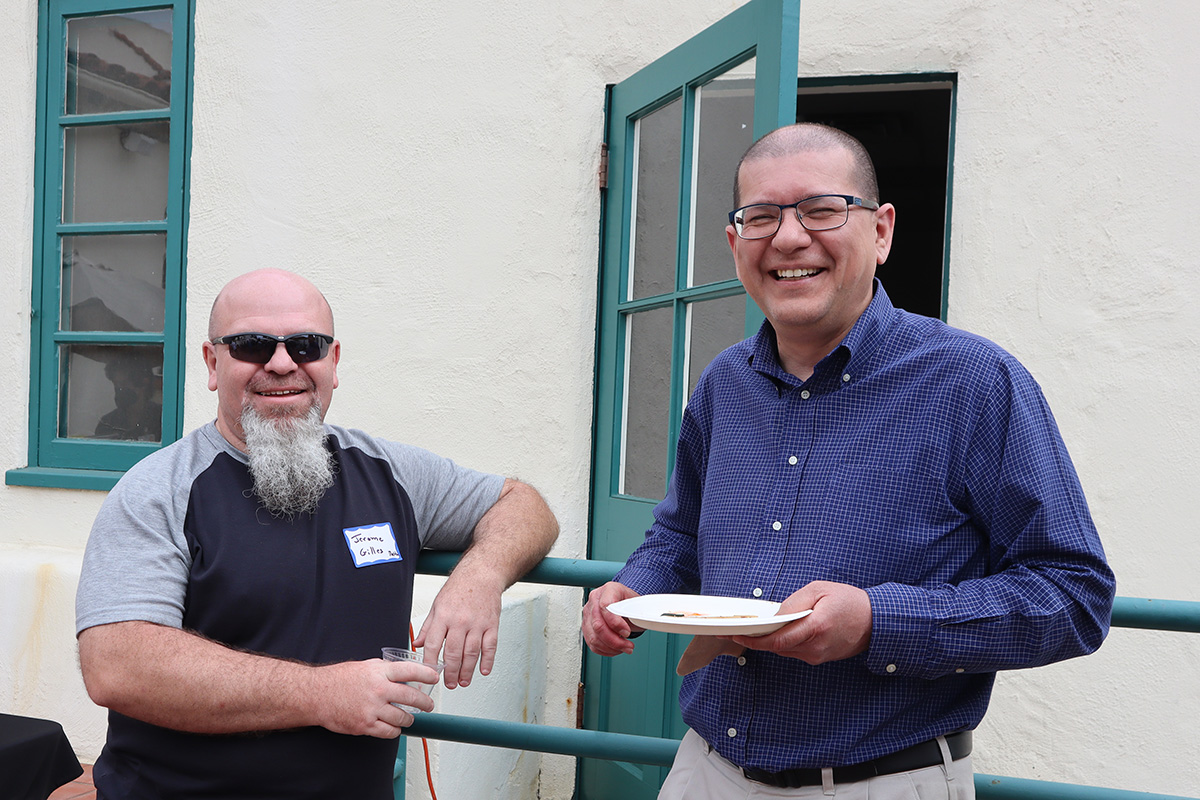 Two professors smile outdoors at a party